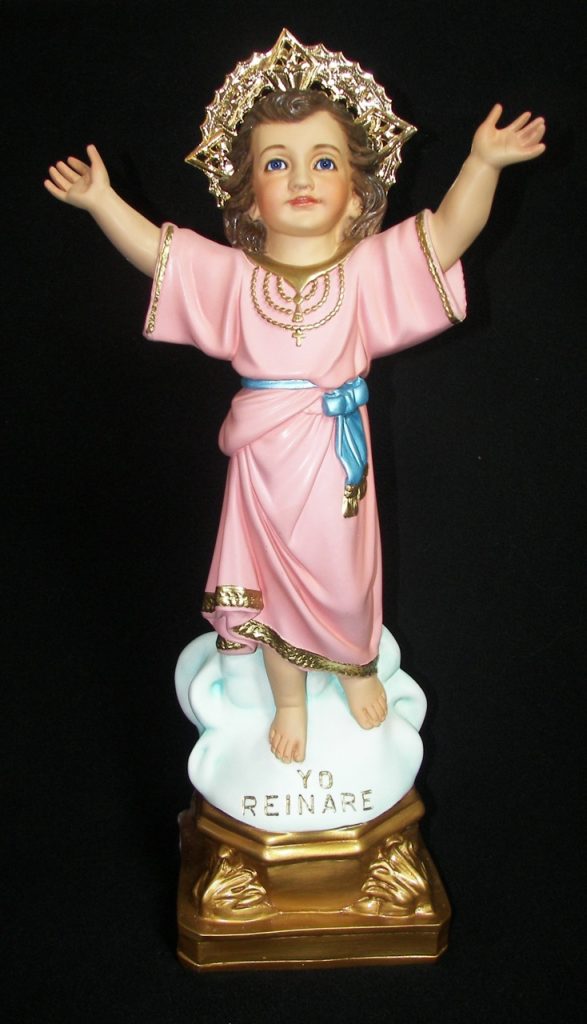 figurine of a child with arms raised in a pink robe