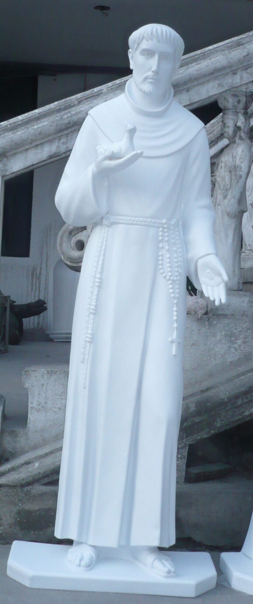 white statue of a saint holding a bird, standing